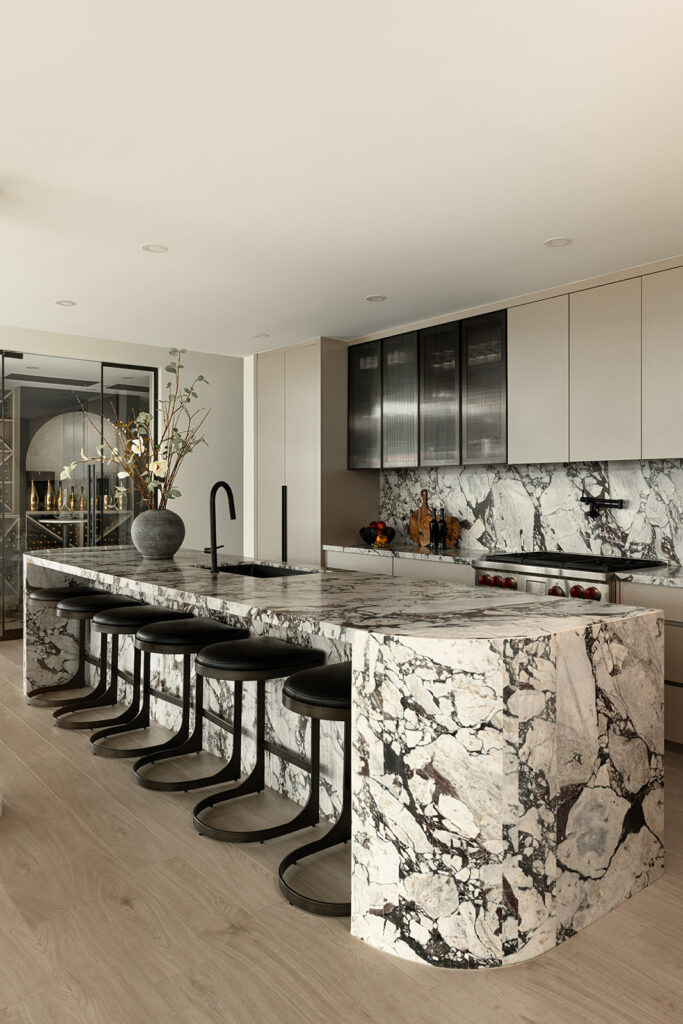 Toronto Penthouse kichen with large Calcutta Viola marble island. In view is the custom temparature controlled wine room.